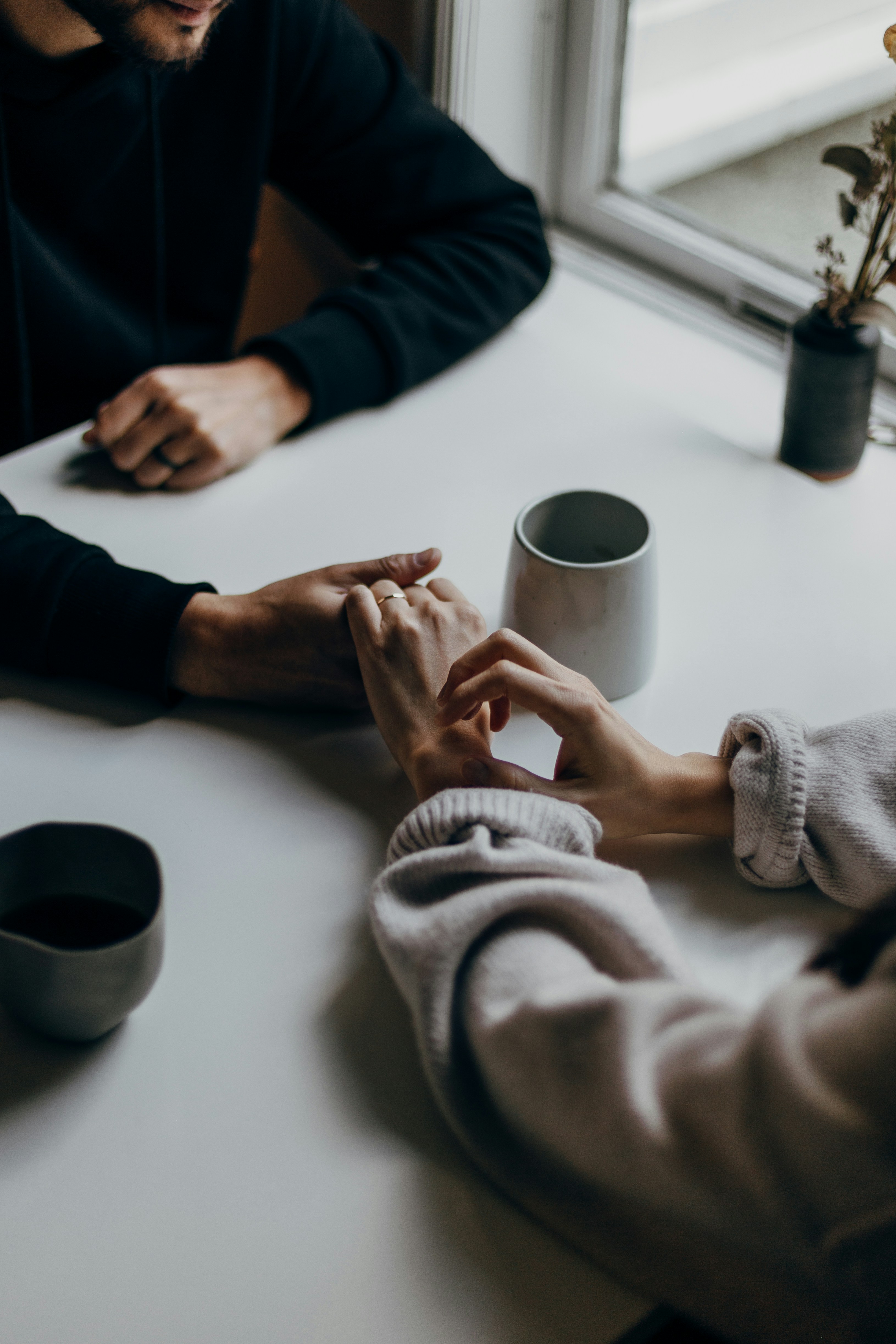 Two people holding hands in a gesture of healing and reconciliation